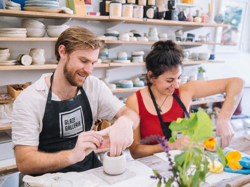 A couple smiling whilst making pottery at a craft class.